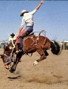 a man riding on the back of a brown horse in a dirt field with other men