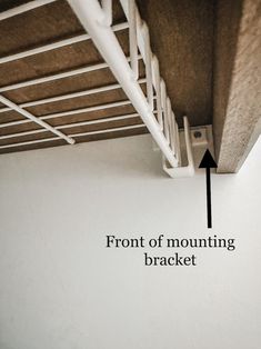 the bottom part of a bunk bed with an arrow pointing to the front of mounting bracket