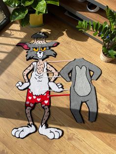 two paper cutouts of cartoon characters on a wooden floor