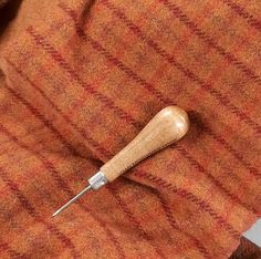 a sewing needle resting on the back of an orange jacket with red and white stripes