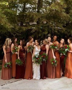 a group of women standing next to each other wearing dresses and holding bouquets in their hands