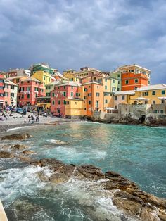 colorful buildings line the shore of an oceanfront area with waves crashing in front of them