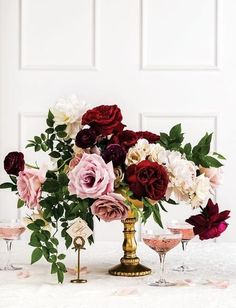 a vase filled with flowers sitting on top of a table next to two champagne glasses