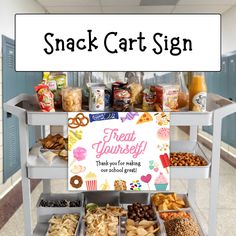 a snack cart sign sitting on top of a metal shelf filled with lots of food