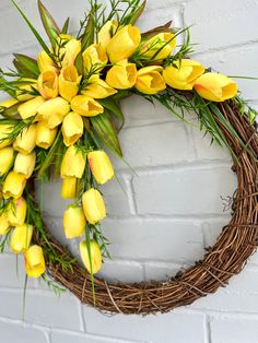 a wreath with yellow tulips hanging on a brick wall next to a white brick wall