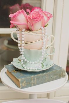 a stack of tea cups with pink roses in them