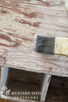 a paintbrush sitting on top of a piece of wood that has been stained white