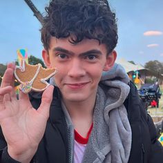 a young man holding up a cookie shaped like a bird