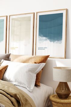 three framed pictures hang on the wall above a bed with white sheets and brown pillows