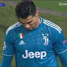 a soccer player is looking down at his head while standing on the field with his hands in his pockets