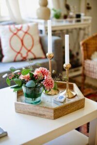 a tray with candles and flowers sitting on top of a coffee table in a living room