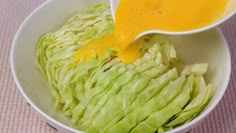 a bowl filled with lettuce and dressing being drizzled on top