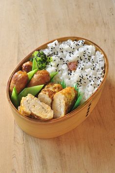 a wooden bowl filled with rice, meat and veggies on top of a table