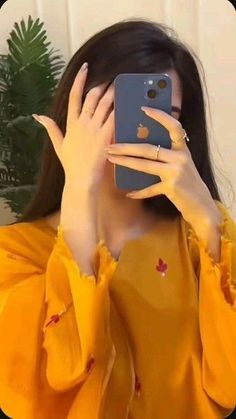 a woman taking a selfie with her cell phone in front of her face and wearing a yellow shirt