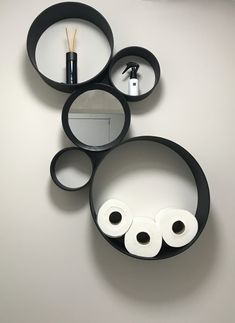 three black circular shelves with toilet paper and toothbrushes in them on the wall