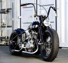 a black motorcycle parked in front of a white container