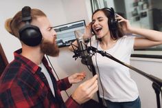 a man and woman singing into headphones in a recording studio