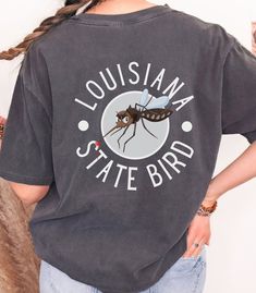 Louisiana State Bird Mosquito T-Shirt Adult Unisex Funny Tshirt Funny Gifts Introducing our humorous Louisiana "State Bird" Mosquito t-shirt! Embrace our beloved state of Louisiana with this tongue-in-cheek design featuring a shifty-eyed sneaky mosquito. It's a lighthearted nod to the state's unofficial winged companion that never fails to make an appearance, many times bringing several friends along. Crafted for comfort and durability, this tee brings together humor and style. Wear it, laugh, a Funny Mosquito, Inside Joke, State Birds, Louisiana State, Funny Tshirt, Tshirt Funny, Gift For Friend, Funny T Shirt, Dye T Shirt