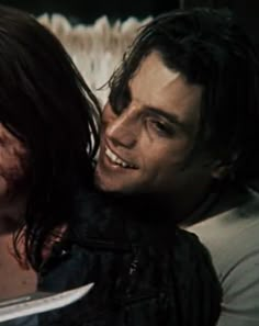 a man and woman laying next to each other with blood on their faces, smiling