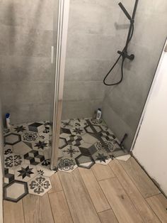 a bathroom with black and white tiles on the floor, shower stall door and toilet