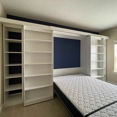 an empty bedroom with a bed, bookcases and built - in shelving