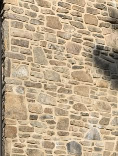 a stone building with a clock on it's side and a bird sitting on the window sill