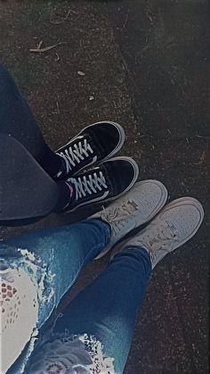 two people standing next to each other with their feet on the ground and one person wearing ripped jeans