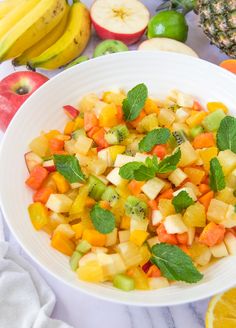 a white bowl filled with fruit on top of a table next to sliced oranges