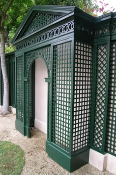 a green gazebo sitting in the middle of a park next to a tree and shrubbery