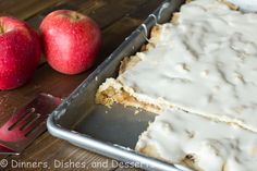 an apple cake with white icing next to two apples