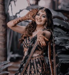 a woman in a black and gold outfit with her hands on her head, posing for the camera