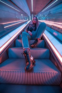 a woman is sitting on an escalator with her legs crossed and wearing high boots