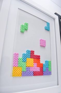 an art piece made out of legos is displayed in front of a white frame