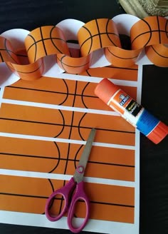 a pair of scissors and glue sitting on top of a piece of paper with basketballs