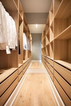 an empty walk - in closet with wooden shelves and drawers