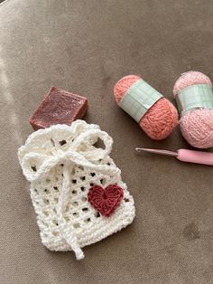 two crocheted bags, one with a heart and the other with a knitting needle