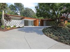 a house with a driveway in front of it and lots of trees around the yard