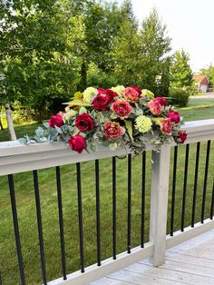 a bunch of flowers sitting on top of a metal rail in front of some grass