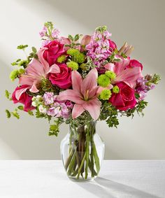 a vase filled with pink and green flowers on top of a white tablecloth covered table