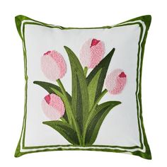 a white pillow with pink tulips embroidered on the front and green trim around the edges