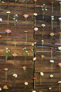 flowers are attached to the side of a wooden fence