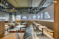 the interior of a restaurant with wooden tables and chairs, along with neon signs on the wall