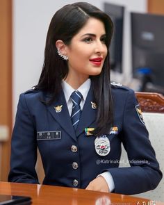 a woman in uniform sitting at a table with her hands on her hips and looking off to the side