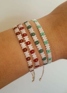 three bracelets with beads on the wrist, one is red and one is green