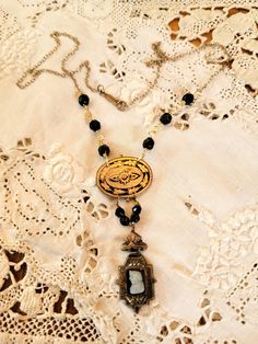 0My inspiration for this necklace was a single gold filled black and white onyx cameo genuine gold filled Victorian earring and a Victorian  gold and black enamel neck pin. i hung them from antique jet beads and the chain is a a vintage chain and clasp. is a very delicate look. part of my tiny treasures collection  The necklace is 18" long and the cameo piece is 1" Elegant Luxury Cameo Necklace, Victorian Black Enamel Pendant Jewelry, Vintage Black Brass Necklace, Vintage Onyx Gold Jewelry, Vintage Gold Onyx Jewelry, Vintage Black Jewelry With Antique Finish, Art Deco Brass Jewelry With Vintage Charm, Brass Art Deco Jewelry With Vintage Charm, Antique Gold Necklaces With Black Enamel