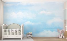 a baby's room with clouds painted on the wall and a crib next to it