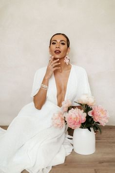 a woman sitting on the floor with flowers in her hand