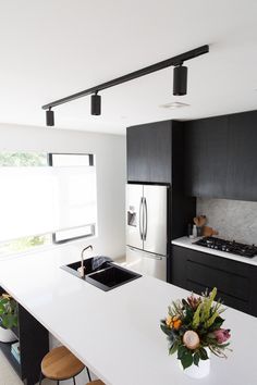 a modern kitchen with black cabinets and white countertops is seen in this image from the front view