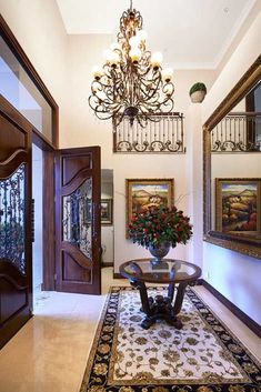 a foyer with chandelier, rug and painting on the wall next to it