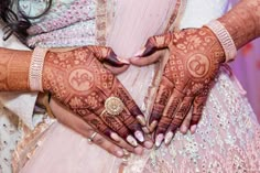 two hands with henna on them holding each other's wedding rings and bracelets